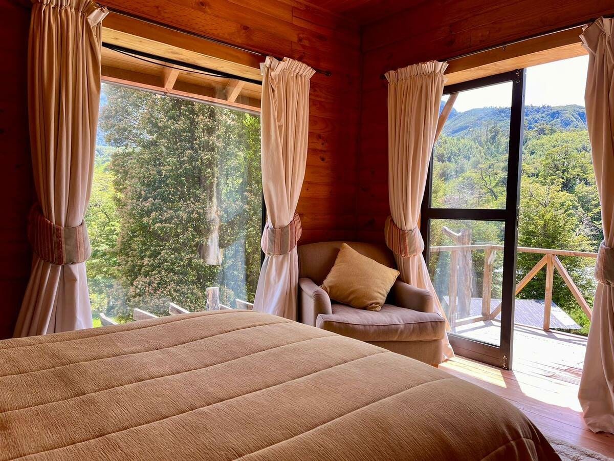 Habitación del Río, cama y sillón junto a la ventana con vista al río